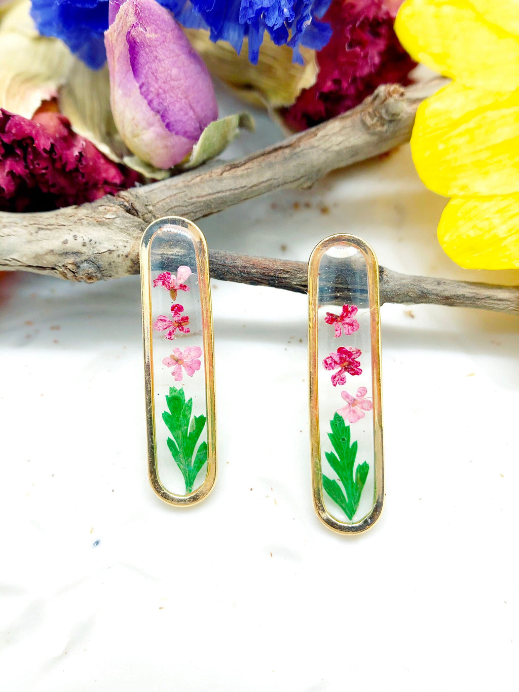 orecchini a forma di baguette in ottone oro con all&#39;interno fiori veri rosa e foglie verdi.