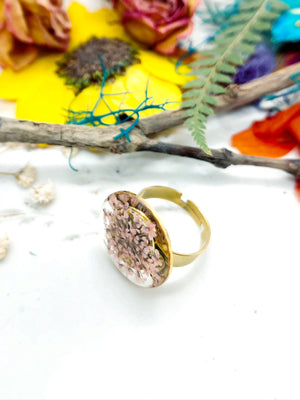 anello in acciaio oro regolabile, con materiale anallergico ed inossidabile. Anello con cerchio e all&#39;interno fiori veri rosa pastello chiaro.