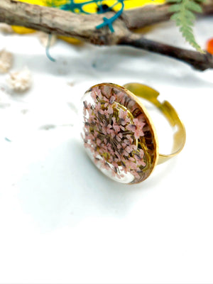 anello in acciaio oro regolabile, con materiale anallergico ed inossidabile. Anello con cerchio e all&#39;interno fiori veri rosa pastello chiaro.